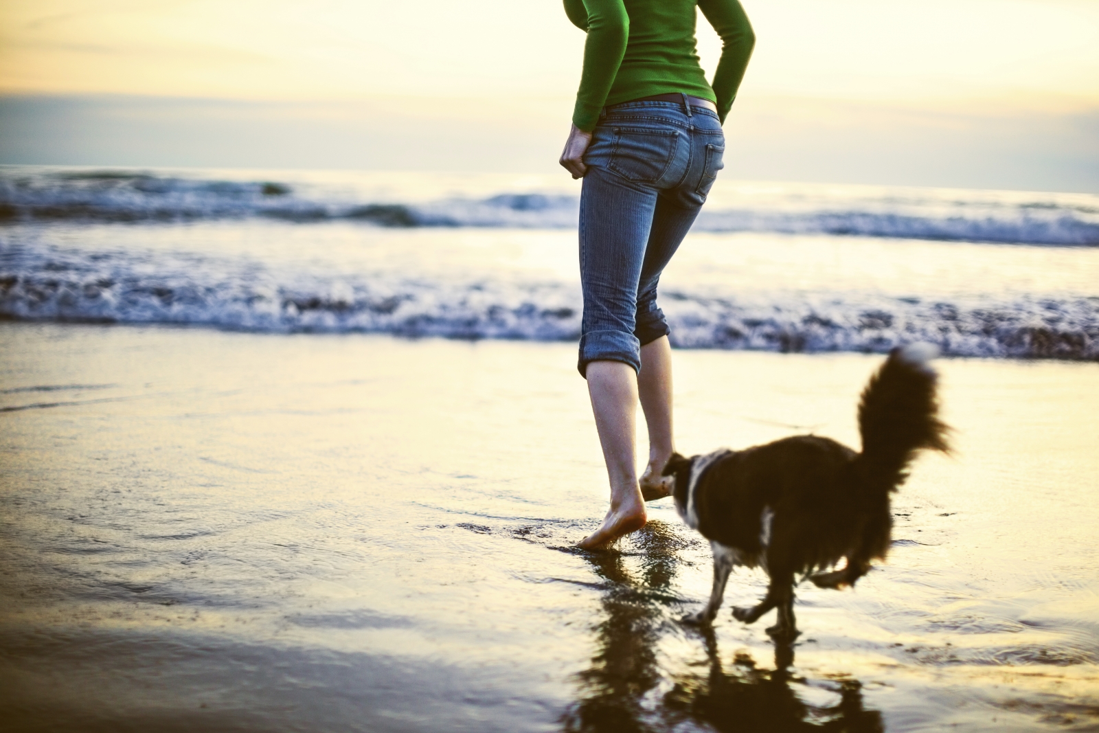 Laufende Frau mit Hund am Strand